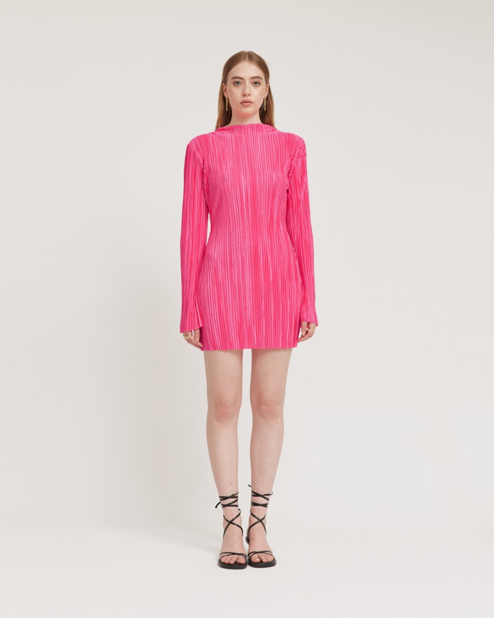 Woman wearing a bright pink pleated dress on a white background