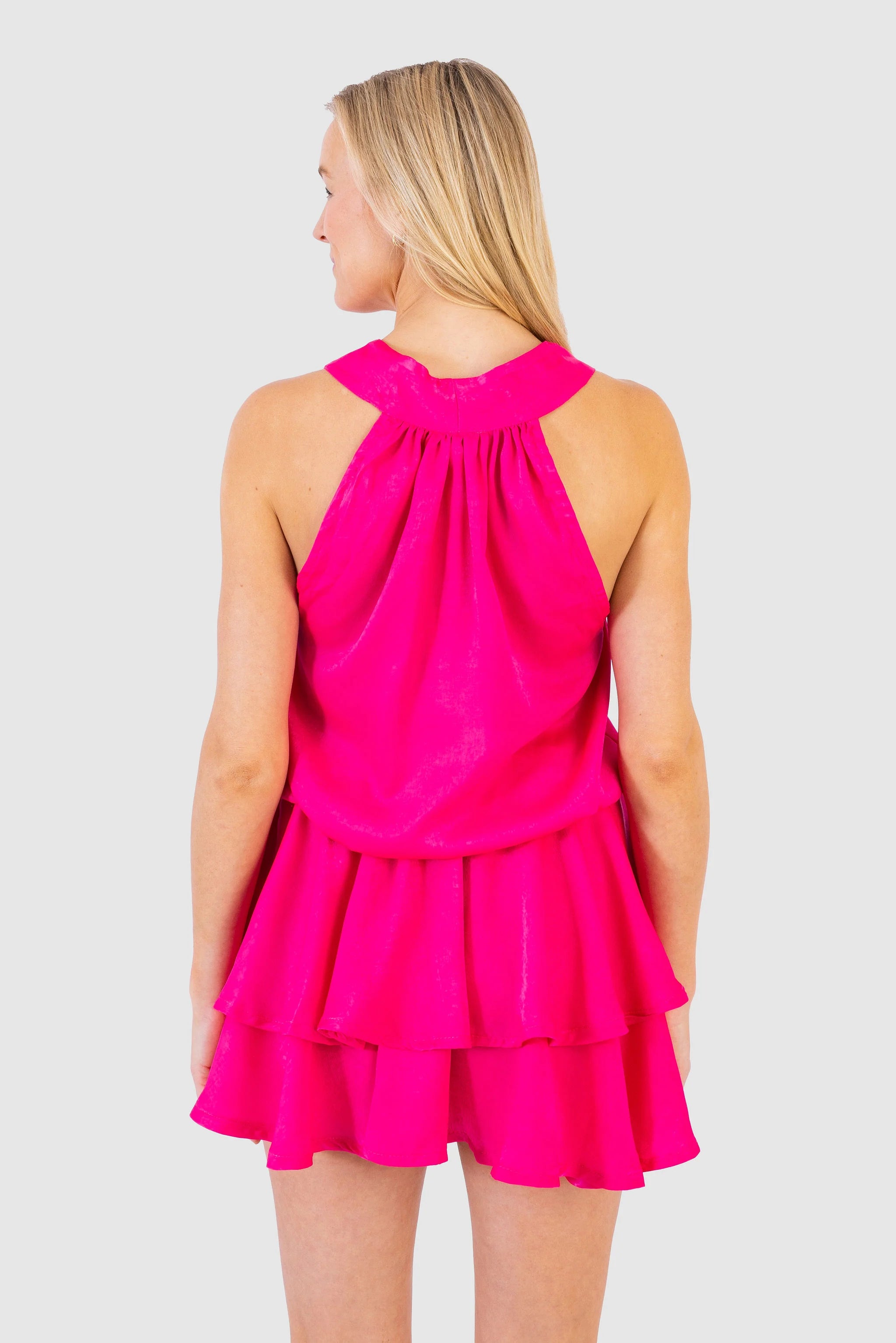 Woman wearing a bright pink dress against a plain background