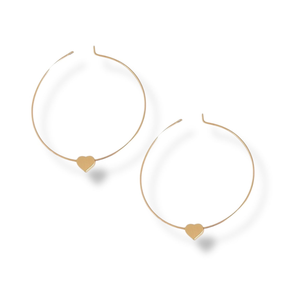 Gold hoop earrings with heart-shaped charms on a white background