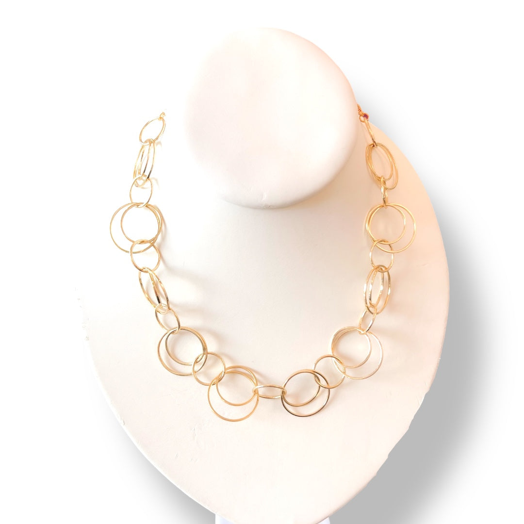 Gold chain necklace on a white stand with a white background