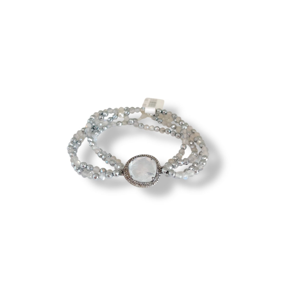 Silver bracelet with a round central stone on a white background