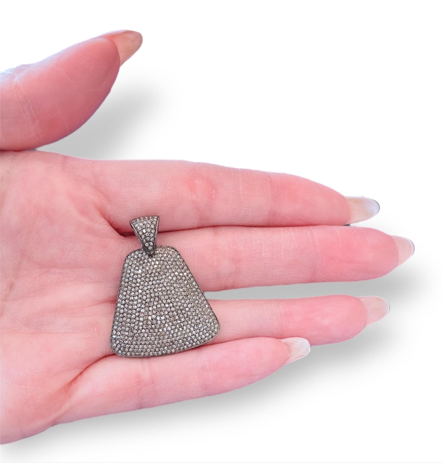 Hand holding a silver pendant with a white background