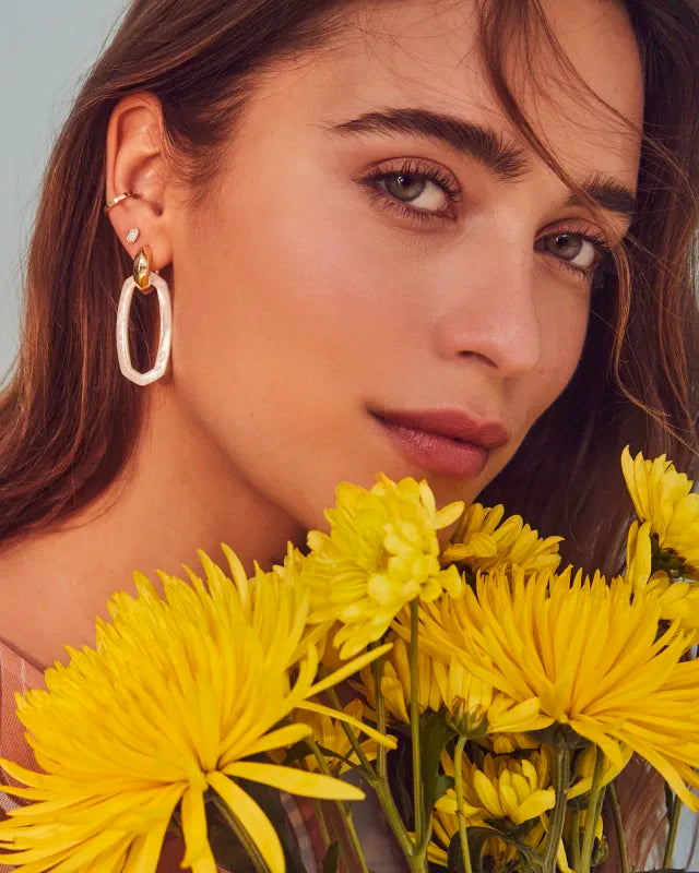 Woman with yellow flowers and hoop earrings against a neutral background
